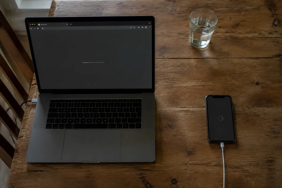 A laptop and a separate phone show different loading states on a shared household table