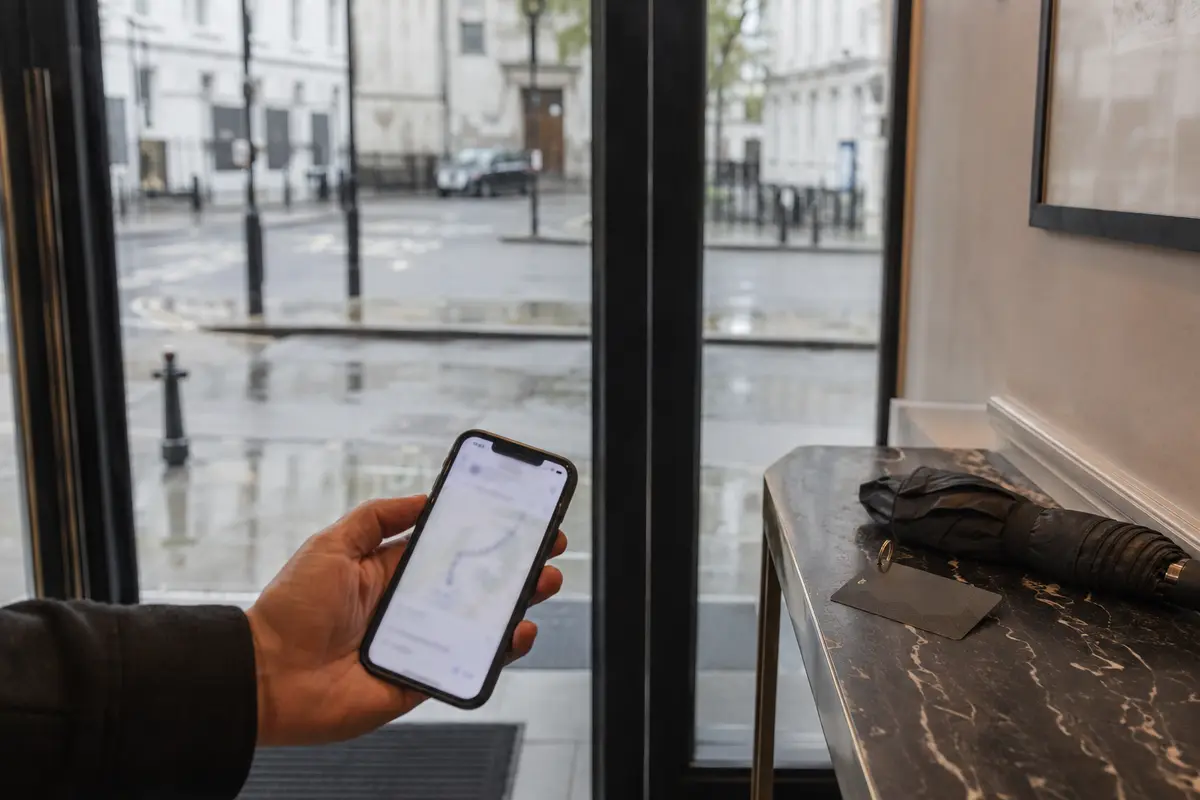 A traveler holding clinic directions near the rainy entrance of a London hotel